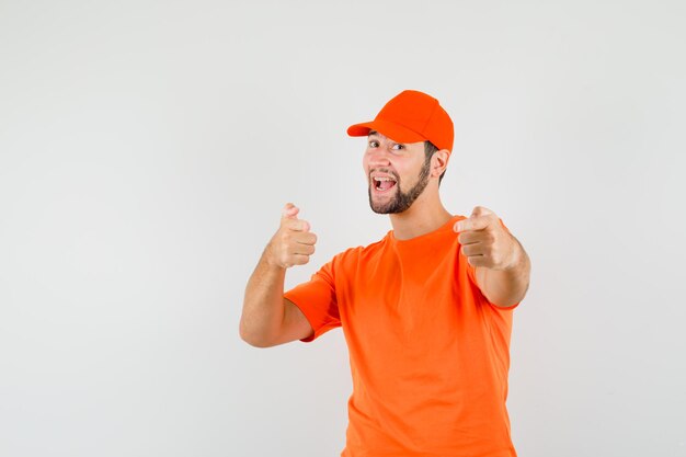 Lieferbote, der in orangefarbenem T-Shirt, Mütze zeigt und glücklich aussieht, Vorderansicht.