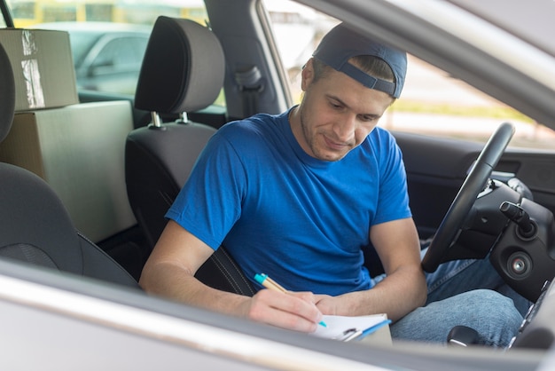 Kostenloses Foto lieferbote im auto, das dokument unterschreibt