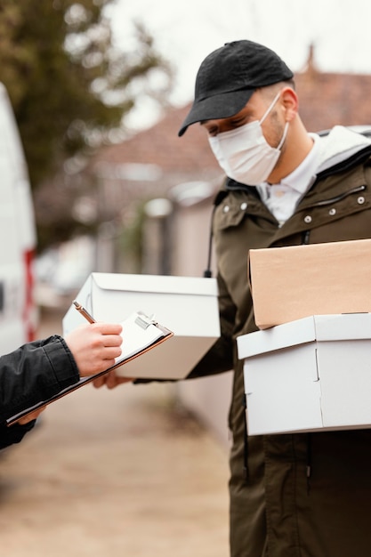 Lieferbote mit Paket tragende Maske