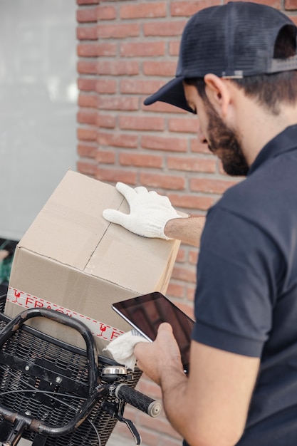 Lieferbote mit Paket unter Verwendung der digitalen Tablette