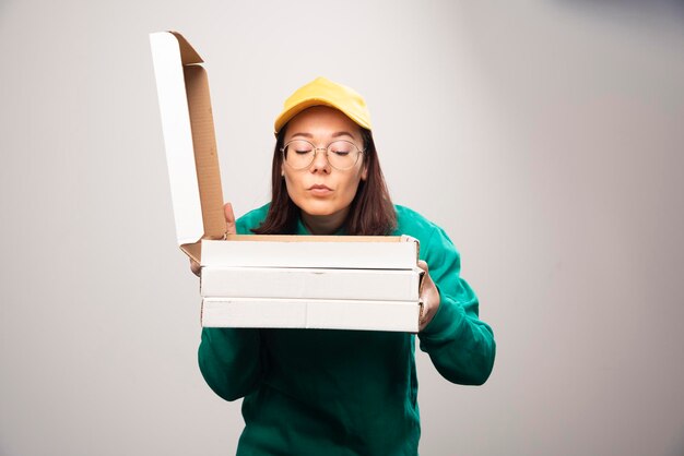 Lieferfrau, die auf Pappkartons Pizza auf einem Weiß schaut. Foto in hoher Qualität