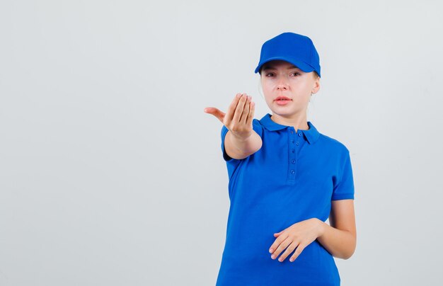 Lieferfrau, die einlädt, im blauen T-Shirt und in der Mütze zu kommen