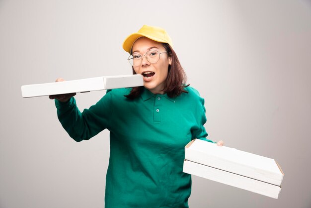 Lieferfrau, die Pappkartons Pizza auf einem Weiß hält. Foto in hoher Qualität