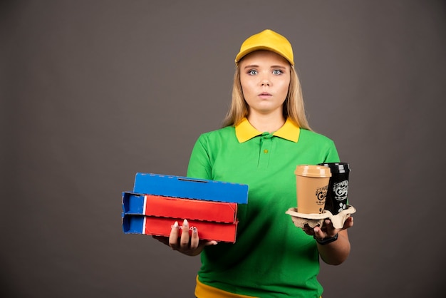 Lieferfrau, die Tassen Kaffee und Pappkartons Pizza hält.