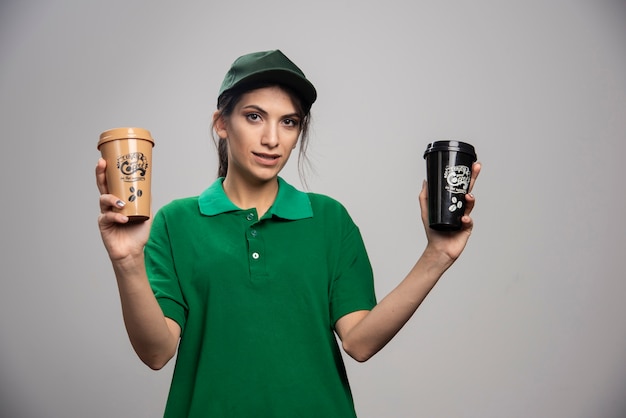 Kostenloses Foto lieferfrau in der grünen uniform, die mit köstlichem kaffee aufwirft.