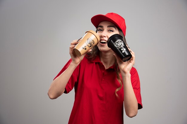 Lieferfrau in roter Uniform, die Kaffee trinkt.