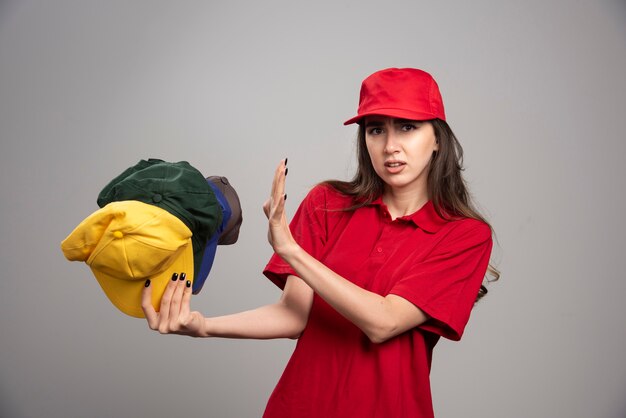 Lieferfrau in roter Uniform, die von bunten Kappen fern bleibt.