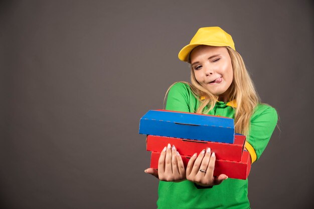 Lieferfrau in Uniform, die Pizzakartons gibt.