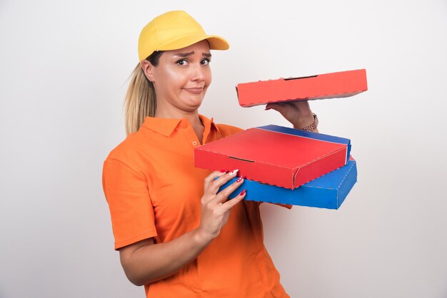 Lieferfrau mit gelbem Hut, der Pizzaschachteln hält.