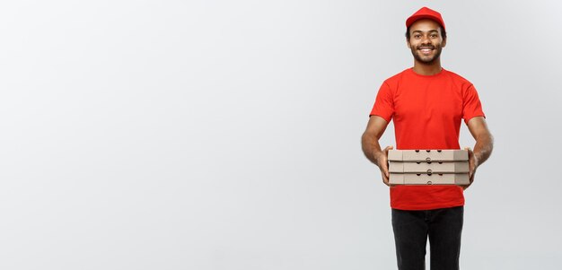 Lieferkonzept Porträt eines gutaussehenden afroamerikanischen Pizzaboten isoliert auf grauem Studio-Hintergrund-Kopienraum