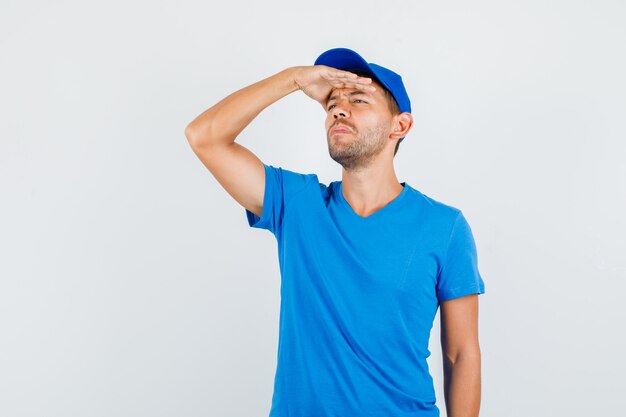 Liefermann, der weg mit Hand auf Augen im blauen T-Shirt schaut