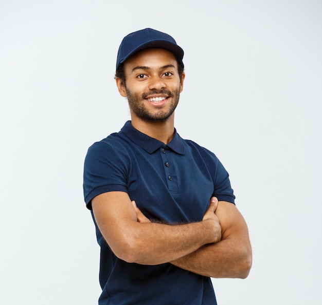 Lieferung Konzept - Handsome African American Lieferung Mann überquerte Arme über isoliert auf Grau Studio Hintergrund. Text kopieren