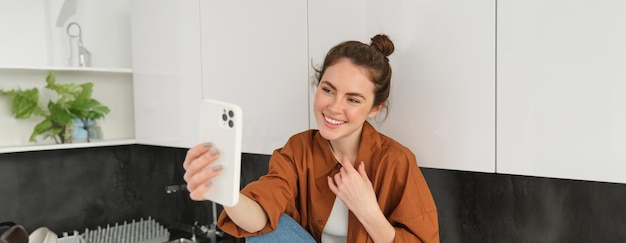 Kostenloses Foto lifestyle-aufnahme einer jungen frau, die mit einer smartphone-app im videochat spricht, um online mit anderen zu sprechen.