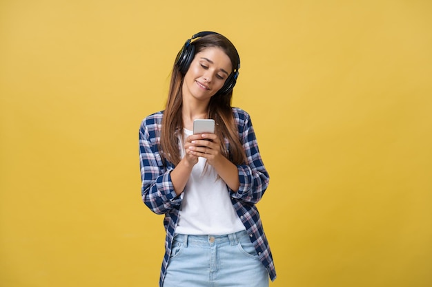 Lifestyle-Konzept Porträt einer schönen kaukasischen Frau, die fröhlich Musik auf dem Handy hört Gelber pastellfarbener Studiohintergrund Kopieren Sie Platz