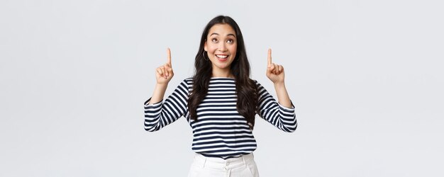 Lifestyle-Menschen-Emotionen-Konzept Aufgeregtes, gutaussehendes asiatisches Mädchen, das erfreut lächelt, als es ein ausgezeichnetes Produkt gefunden hat, das mit dem Finger auf die Werbung zeigt und zufrieden aussieht, empfiehlt Promo