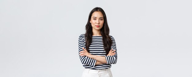 Lifestyle-Menschen Emotionen und lässiges Konzept selbstbewusste, nett lächelnde asiatische Frau mit Kreuzarmen auf der Brust
