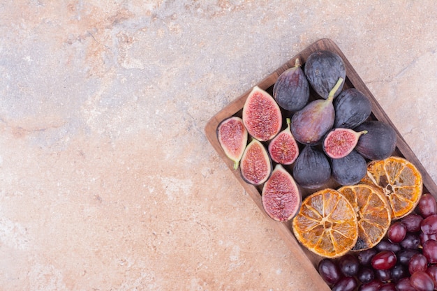 Lila Feigen mit trockenen Orangenscheiben und Kornelkirschenbeeren auf einem Holzbrett