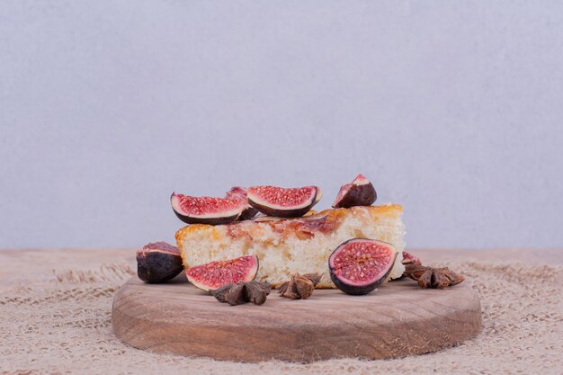 Lila Feigenkuchen auf einer hölzernen Platte mit Früchten.