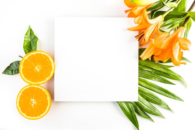 Lilien und Orangen nahe Blättern und Papier