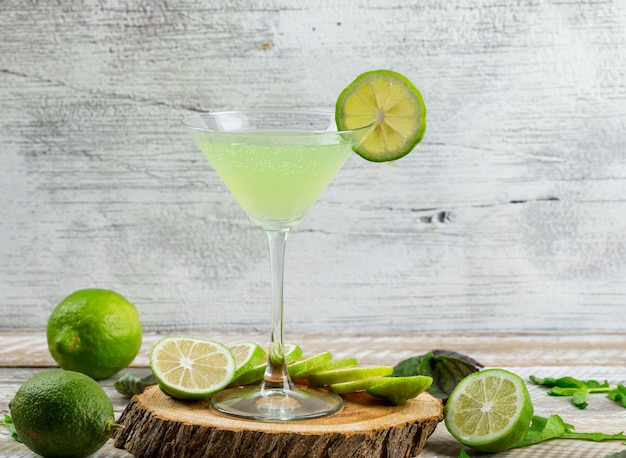 Limonade in einem Glas mit Zitronen, Blättern, Schneidebrett Seitenansicht auf Holz und grungy