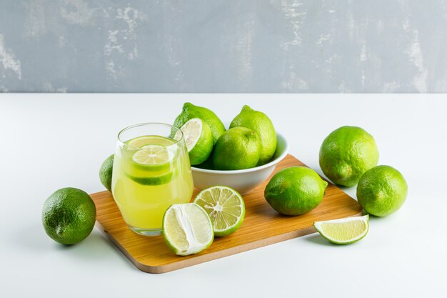 Limonade in einem Glas mit Zitronen, Schneidebrett hohe Winkelansicht auf Weiß und Gips