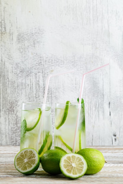 Limonade in Gläsern mit Zitrone, Basilikum Seitenansicht auf Holz und grungy