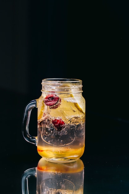 Limonade mit Beeren innerhalb des Glasgefäßes in einem schwarzen Raum.