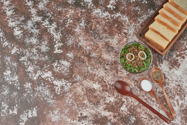 Linsensalat in einer Glasschale mit Kräutern und Brot.