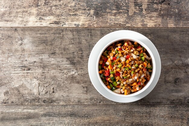 Linsensalat mit Peppersonion und Karotte in einer Schüssel auf Holztisch