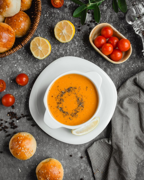 Linsensuppe mit einer Zitronenscheibe und einem Korb mit Brot