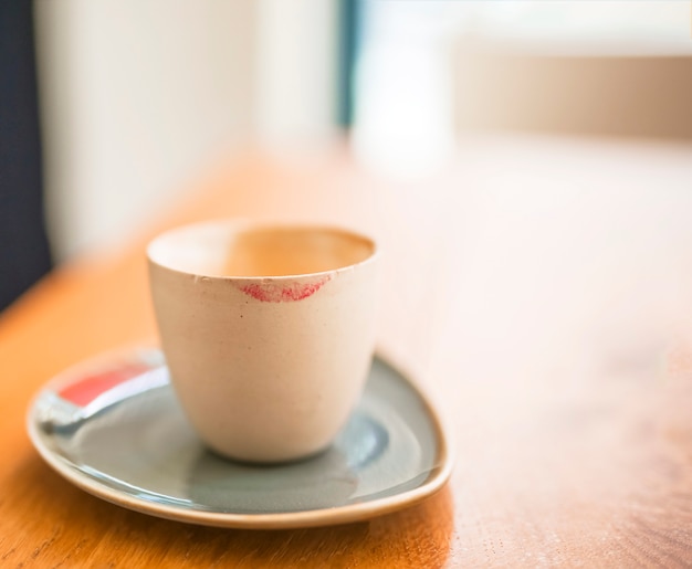 Lippenstiftkennzeichen auf Kaffeetasse über dem Holztisch