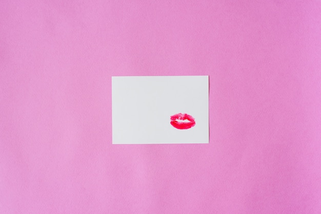 Lippenstiftküsse auf weißbuch auf einem rosa hintergrund