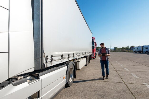 LKW-Fahrer inspiziert Fahrzeug, Anhänger und Reifen vor dem Fahren