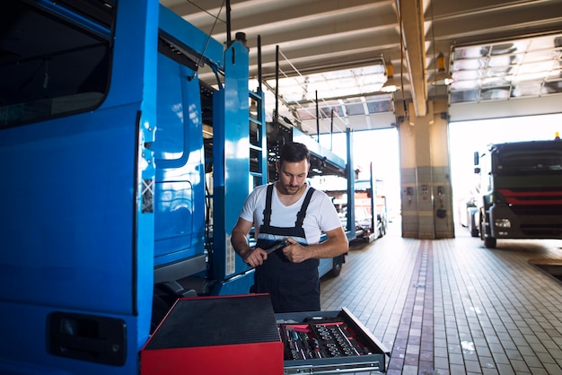 Kostenloses Foto lkw-mechaniker, der lkw-fahrzeug in der werkstatt wartet