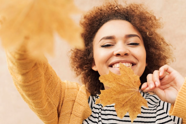 Lockige Frau, die herbstliche Blätter hält