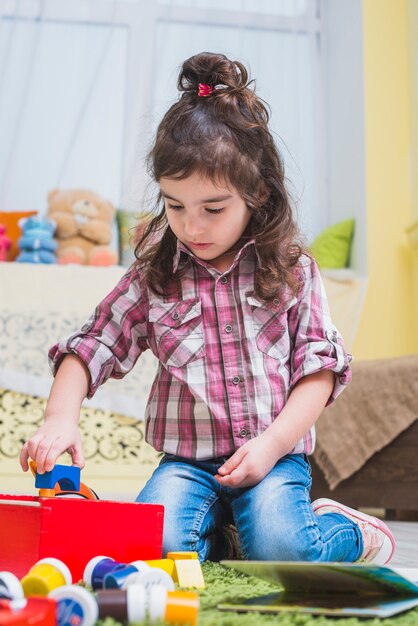 Lockiges Mädchen, das mit Spielwaren spielt