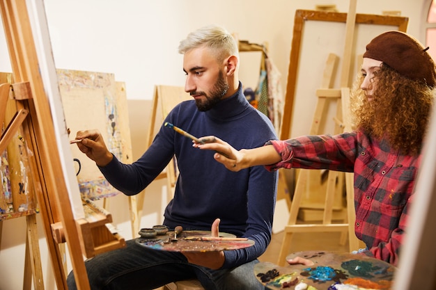 Lockiges Mädchen und Mann zeichnen ein Gemälde