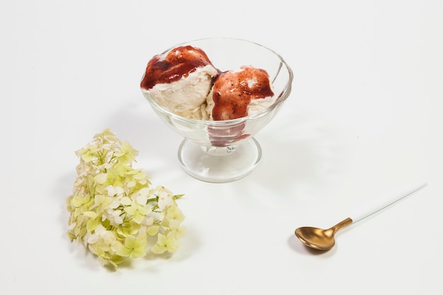 Löffel und Blumen nahe Schüssel mit Eiscreme