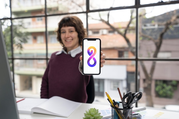 Kostenloses Foto logodesigner, der ein smartphone mit einem coolen logo hält