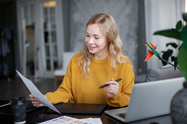 Logodesignerin, die an ihrem Tablet arbeitet, das mit einem Laptop verbunden ist