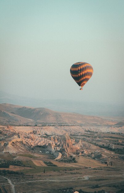 Long Shot eines mehrfarbigen Heißluftballons, der im Himmel hoch über den Bergen schwebt