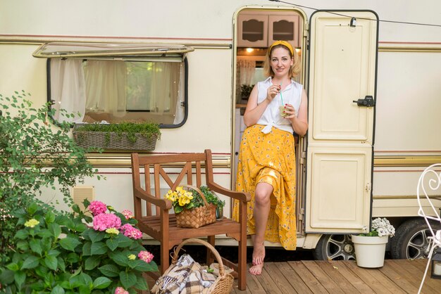 Long Shot Frau hält ein Glas Limonade neben einem Wohnwagen