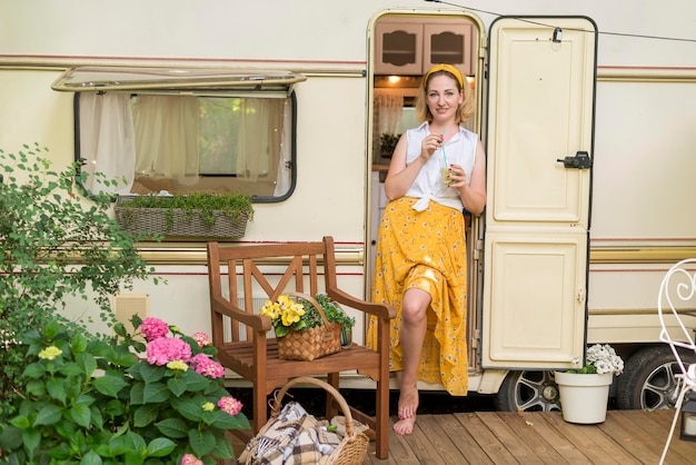 Long Shot Frau hält ein Glas Limonade neben einem Wohnwagen