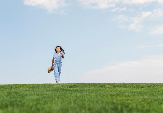 Long Shot Mädchen mit langen Haaren auf Gras laufen