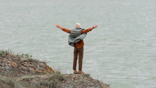 Long Shot Mann mit Händen in der Luft gegenüber Wasser