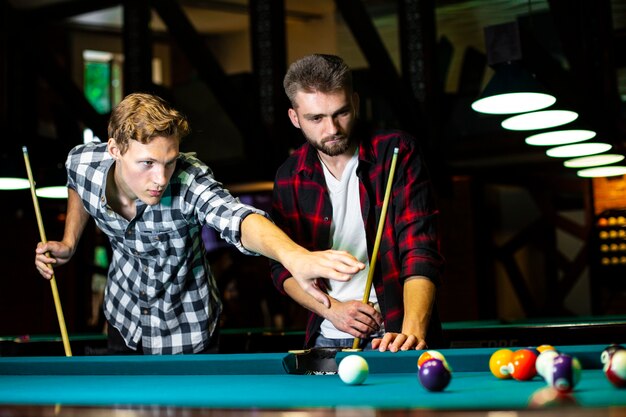 Low Angle Jungs mit Pool Queues spielen Billard