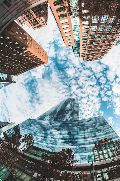 Kostenloses Foto low angle shot der schönen hohen wolkenkratzer unter dem blauen bewölkten himmel