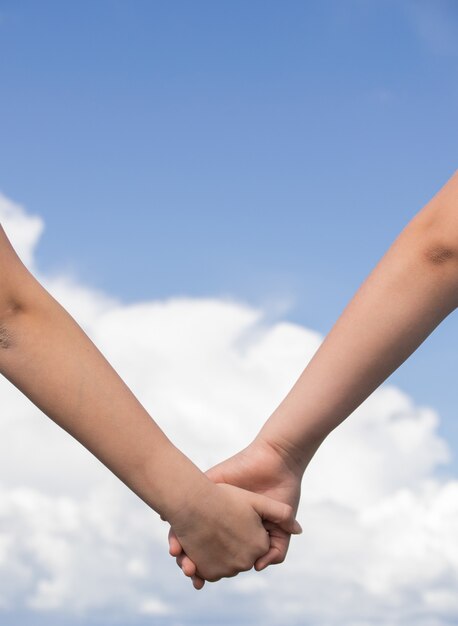 Low Angle Shot von zwei Menschen, die Hände zusammenhalten - Freundschaft, Liebeskonzepte