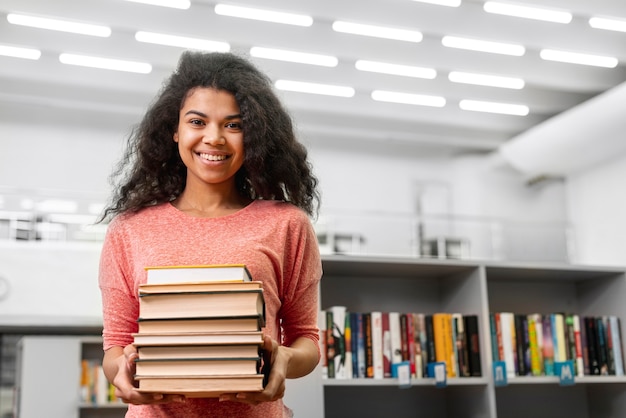 Low Angle Smiley Mädchen mit Stapel Bücher