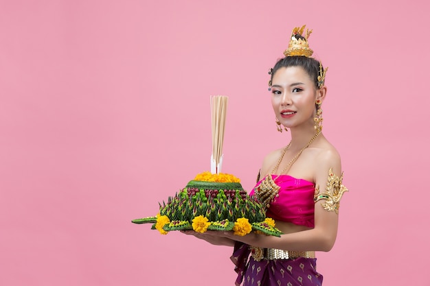 Loy Krathong Festival. Frau im thailändischen traditionellen Outfit hält dekorierten Auftrieb